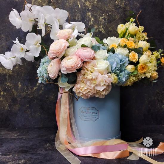 Композиция из ранункулюсов, орхидей, гортензий и роз в коробке